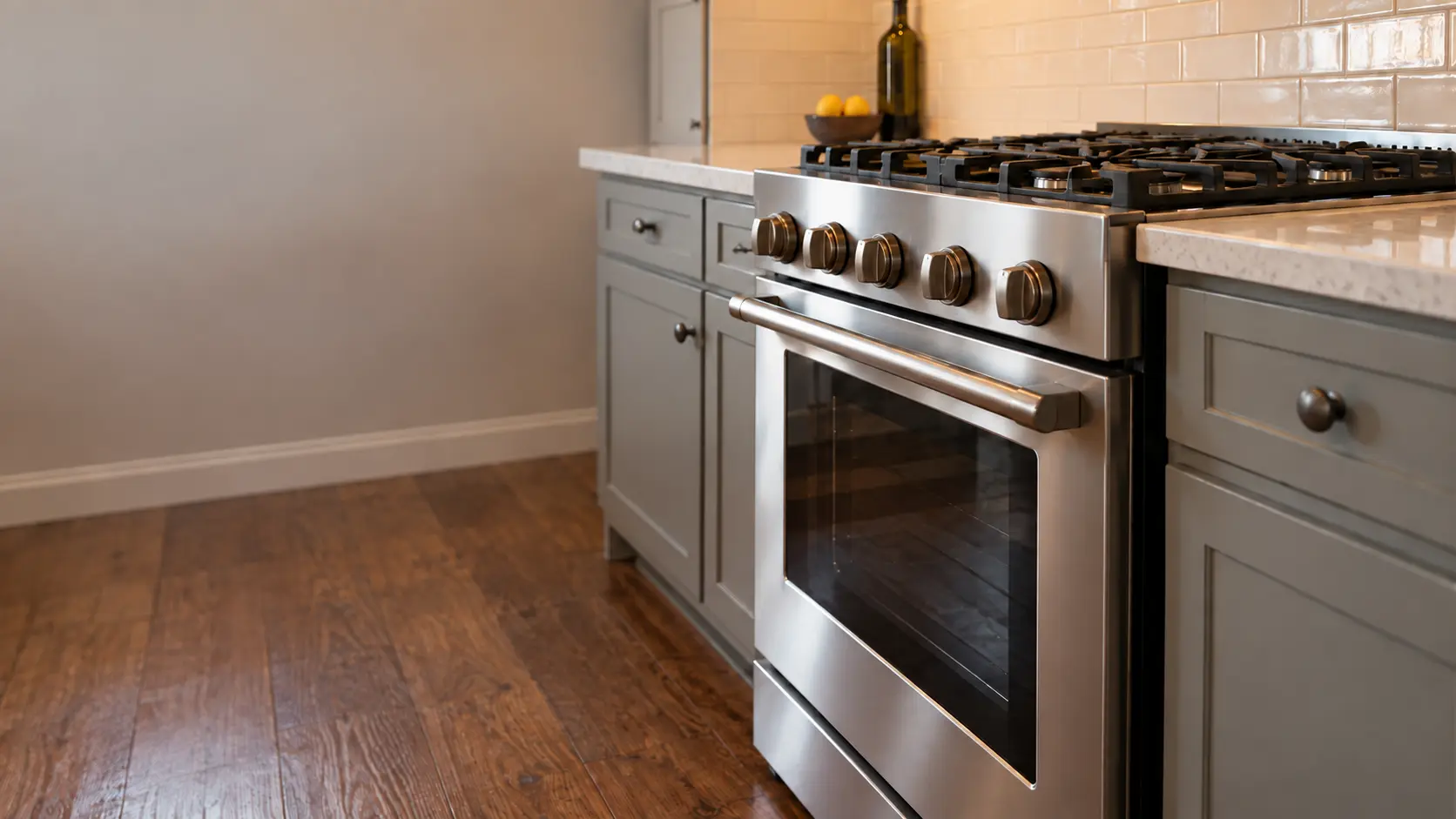 A semi-attached house kitchen with a stainless gas stove, seen low from beside the oven door, the stovetop catching the light.